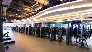 Un gimnasio moderno con varias máquinas de ejercicio y un diseño de techo curvo.