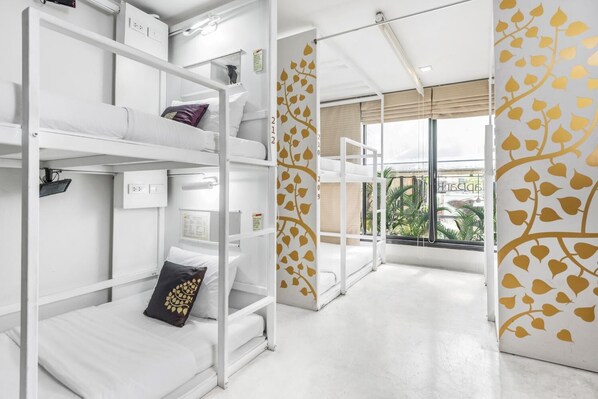 A hotel room with bunk beds, a window with a view, and a wall with a leaf pattern.