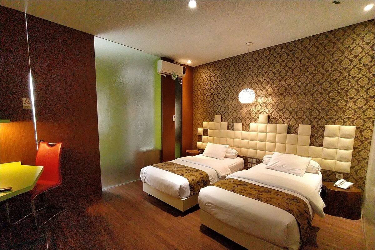 A hotel room with two beds, a desk, and a chair.