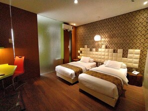 A hotel room with two beds, a desk, and a chair. - Griya Jogja Hotel (Yogyakarta)