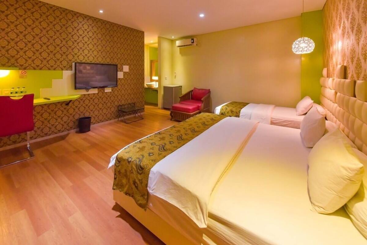 A hotel room with two beds, a TV, a desk, and a chair.