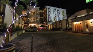 Un hôtel avec une allée pavée, une voiture garée et une moto.