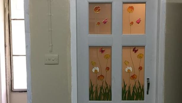 A white door with a frosted glass panel featuring floral artwork. - Kedkanok Apartment (Bangkok)