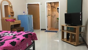 A bedroom with a bed, a television on a stand, a wardrobe, and a door leading to a bathroom. - Kedkanok Apartment (Bangkok)