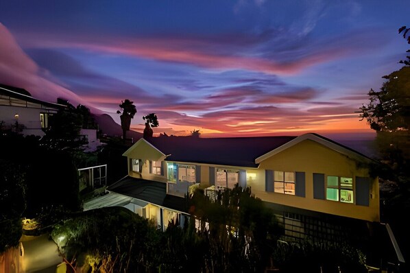 A modern house with a large balcony, surrounded by trees and a mountain backdrop. - Cape Rose Cottage (Cape Town)
