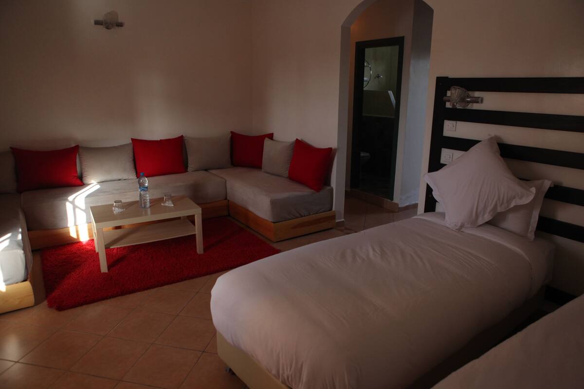 Ein Hotelzimmer mit einem Bett, einem Sofa, einem kleinen Tisch und einem roten Teppich.