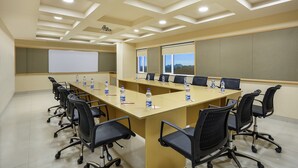 A conference room with a long table, black chairs, water bottles, and a projector screen. - Ginger Vapi (Vapi)