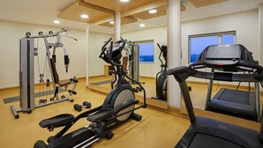 A gym with cardio machines, weight equipment, and large windows offering views. - Ginger Vapi (Vapi)