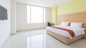 A modern hotel room with a large bed, a flat-screen TV, a ceiling fan, and a large window providing natural light. - Ginger Vapi (Vapi)