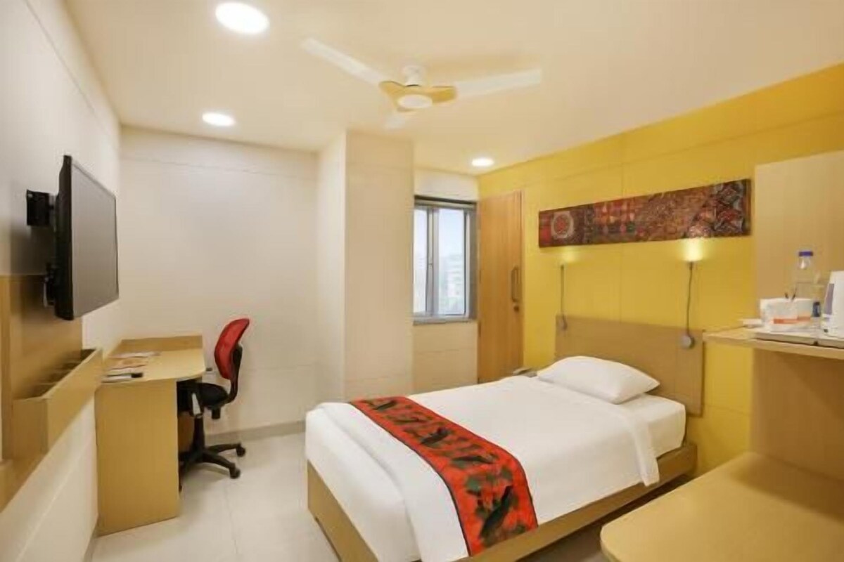 Une chambre d’hôtel équipée d’un lit, d’un bureau, d’une chaise, d’une télévision et d’un ventilateur de plafond.