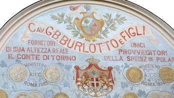 Un techo con un emblema decorativo y texto, incluyendo las palabras "Cav. GB Burlotto" y "Provveditori".