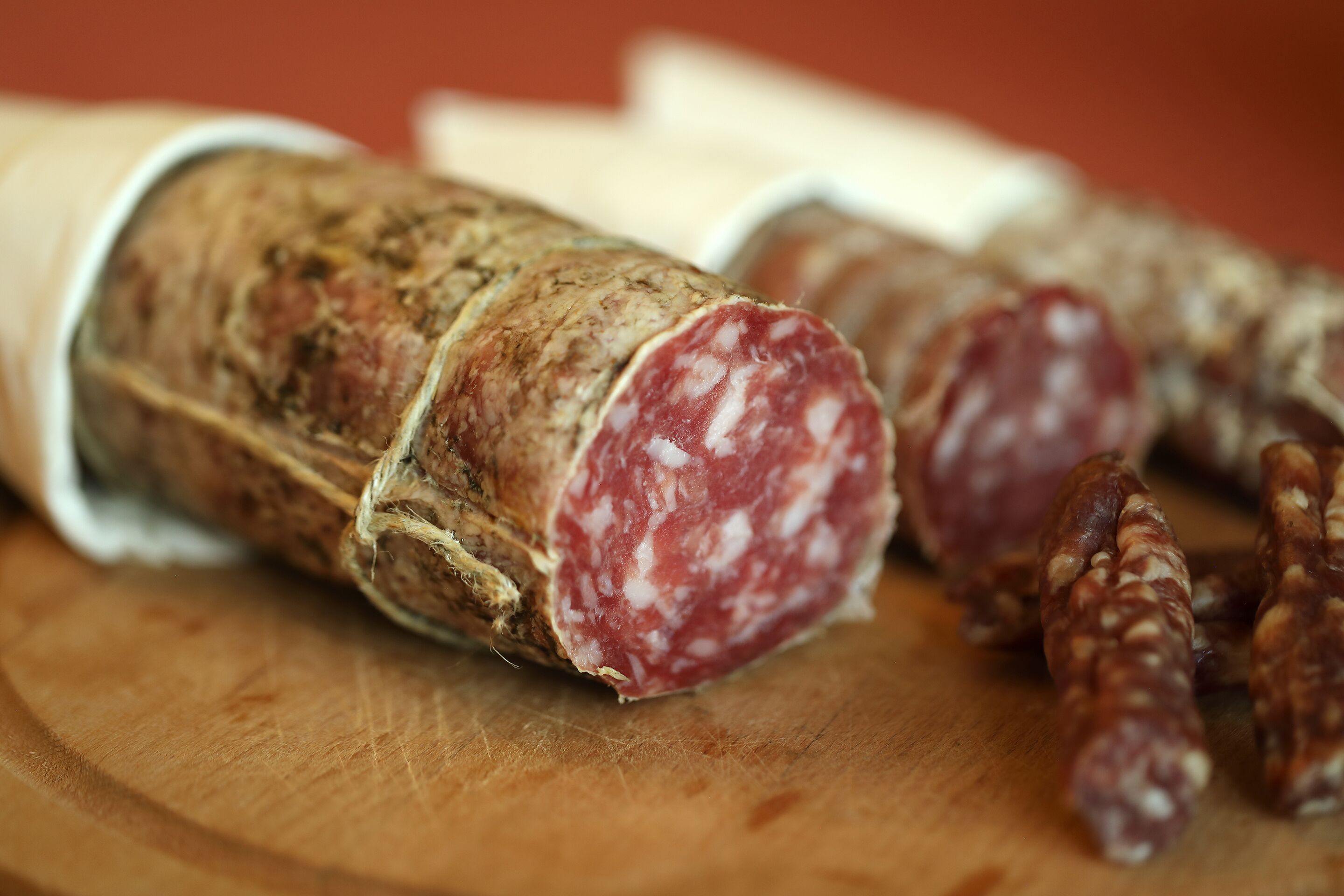 Een close-up van vleeswaren, waarschijnlijk salami, op een houten snijplank.