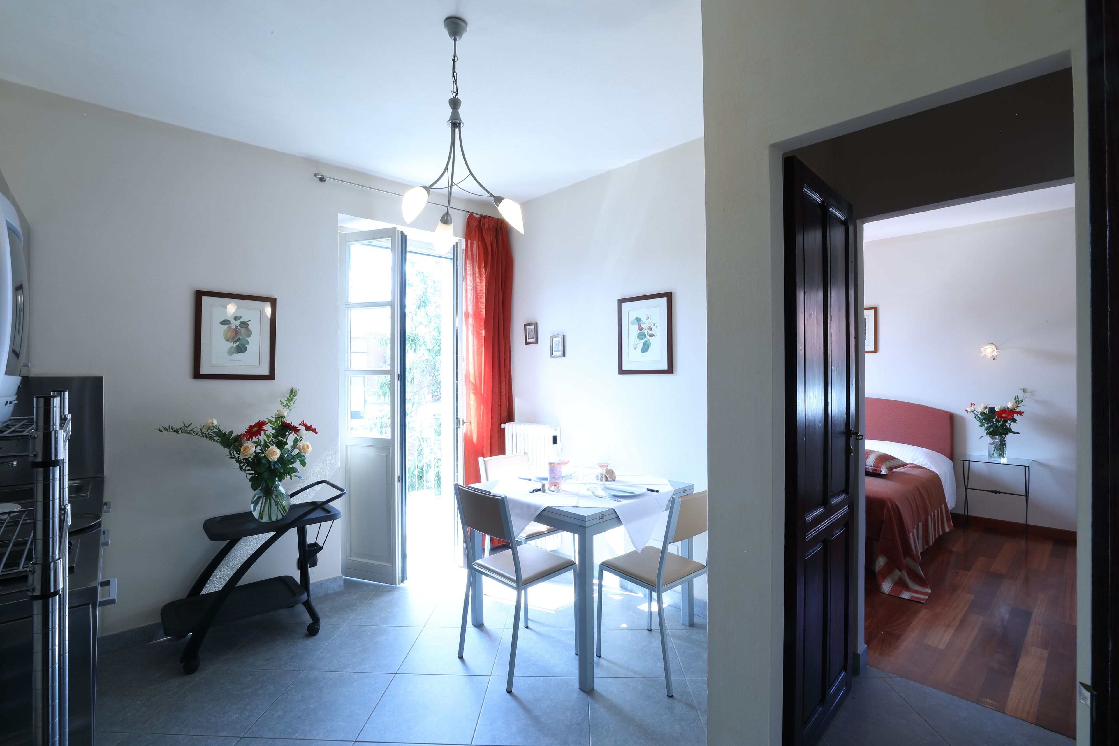 Une cuisine moderne dotée d’un four encastré, un coin repas avec une table et des chaises, et une chambre à coucher avec un lit et une table de chevet.