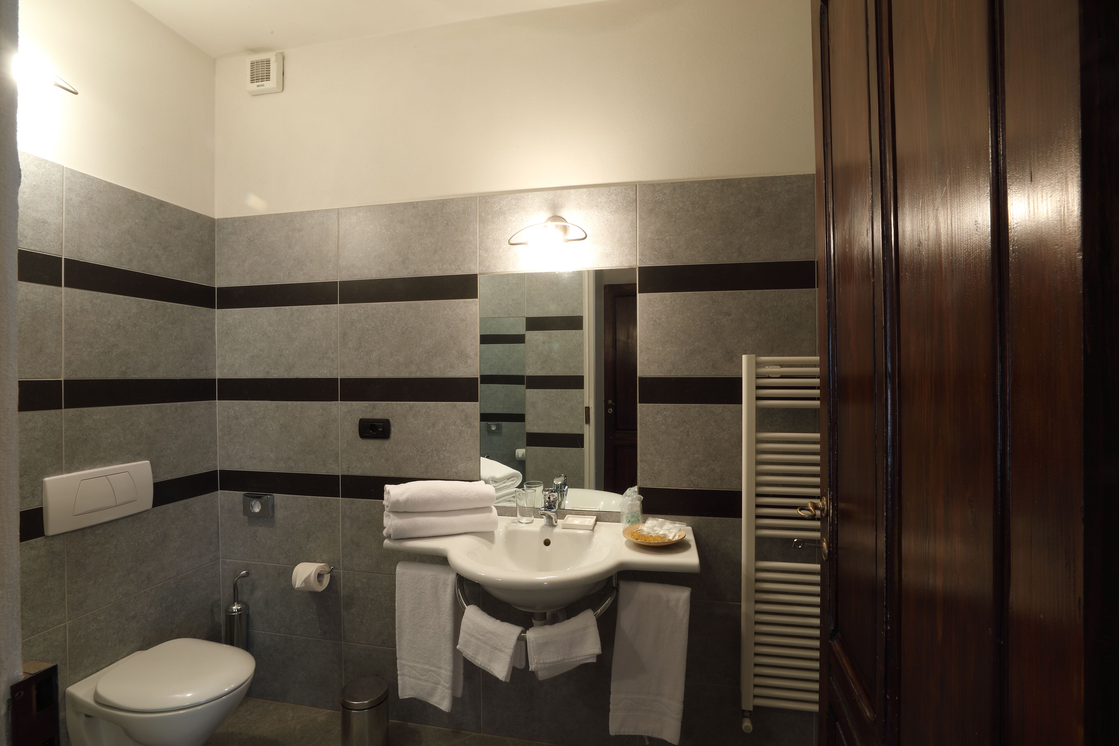 Un baño con inodoro, lavamanos y perchero para toallas.