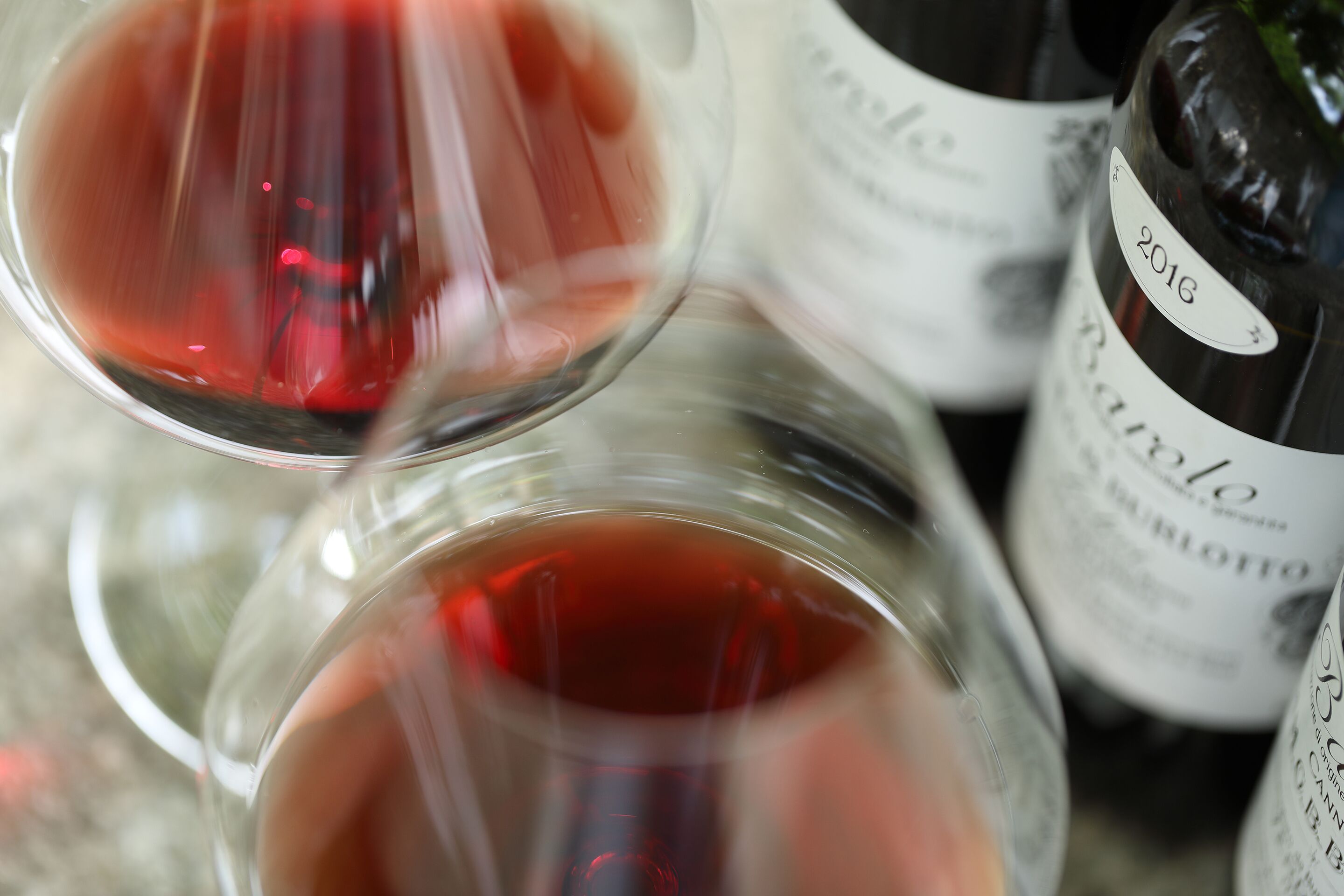 A close-up of wine glasses and bottles, with a focus on the labels and liquid.