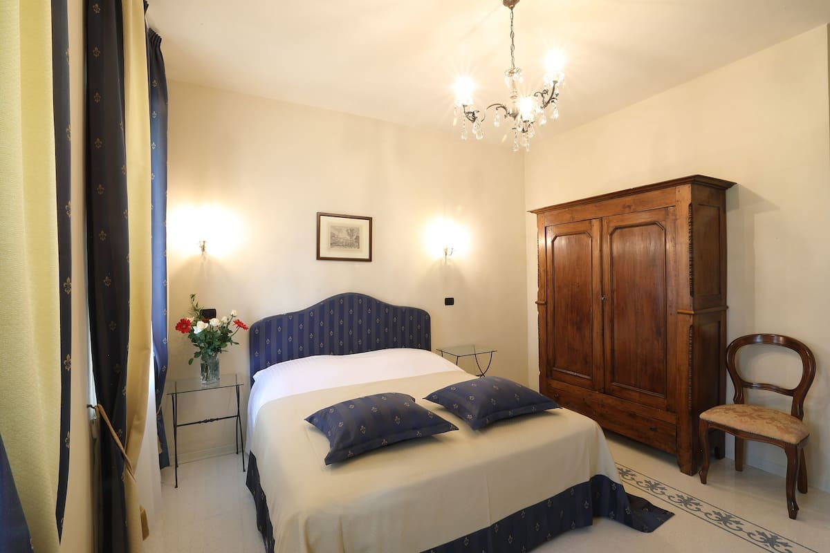 A bedroom with a bed, bedside table, lamp, wardrobe, and chair.