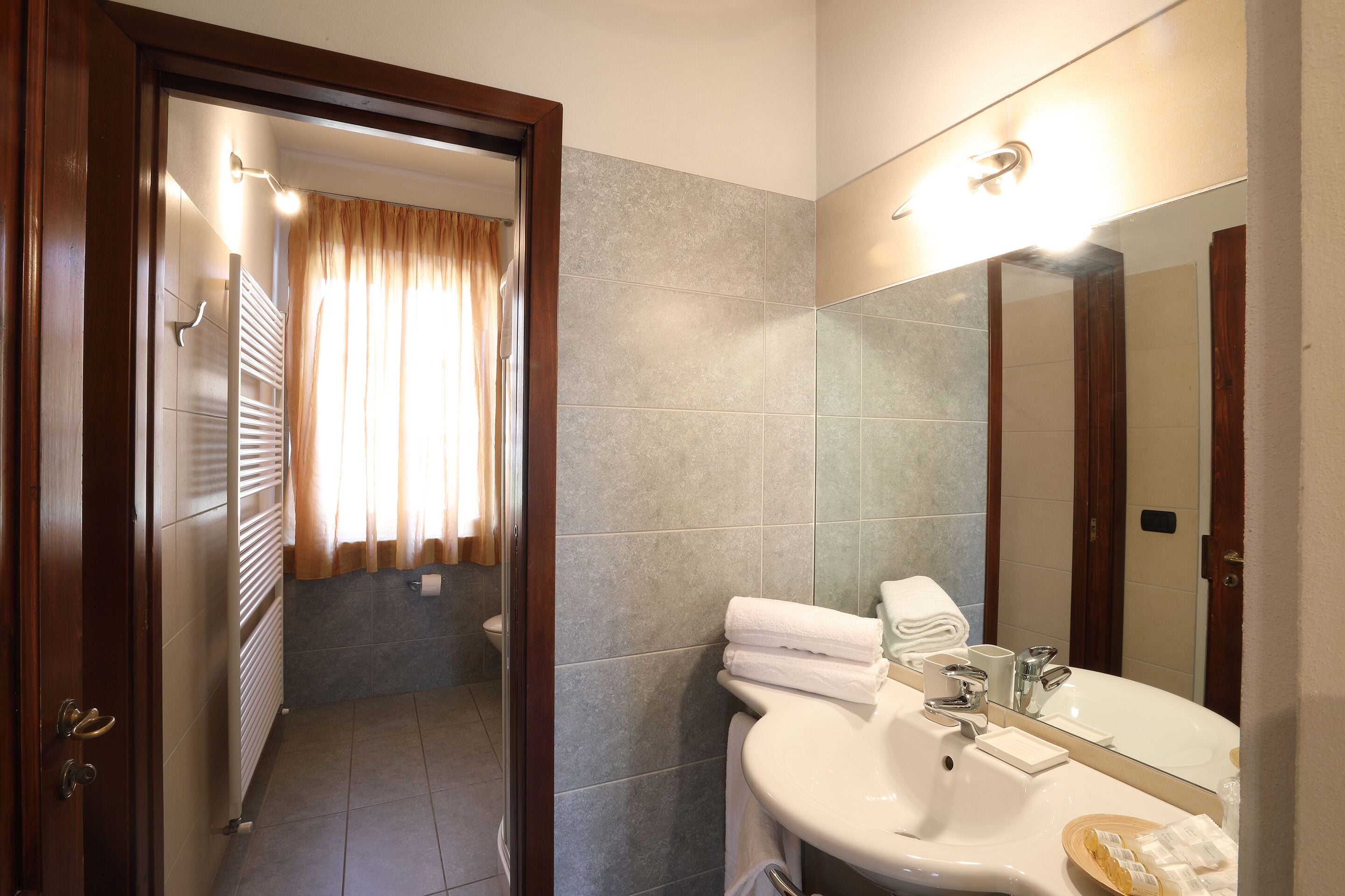 A bathroom with a sink, mirror, towel rack, and a shower area.
