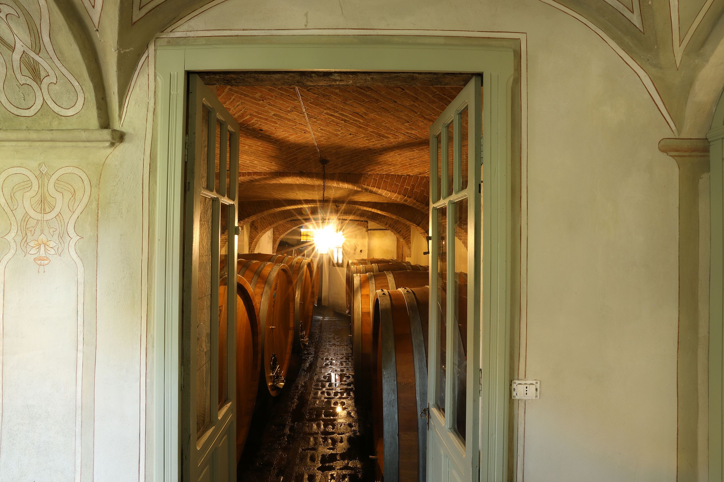 Un couloir orné de barils en bois, doté d’un plafond en briques et d’un luminaire.