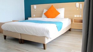 Una habitación de hotel moderna con una cama grande, un cabecero de madera y una pared azul decorativa.