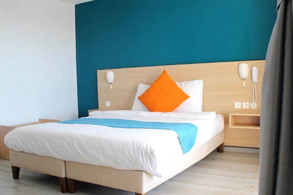 Ein modernes Hotelzimmer mit einem großen Bett, einem Holzkopfteil und einer blauen Akzentwand.