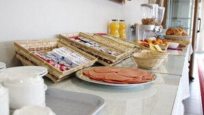 Un bufé de desayuno con diversas opciones de comida, entre ellas pasteles, frutas y bebidas.
