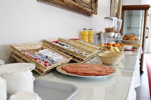 Un bufé de desayuno con diversas opciones de comida, entre ellas pasteles, frutas y bebidas.