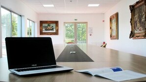 Un salón de conferencias con una computadora portátil, un libro y un cuadro en una mesa.