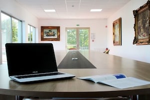 Un salón de conferencias con una computadora portátil, un libro y un cuadro en una mesa.