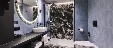 A modern bathroom with a vanity, two mirrors, a bathtub, and a toilet.