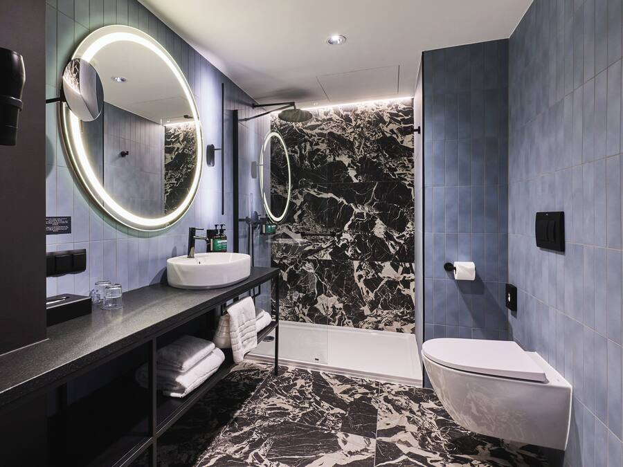 A modern bathroom with a vanity, two mirrors, a bathtub, and a toilet.