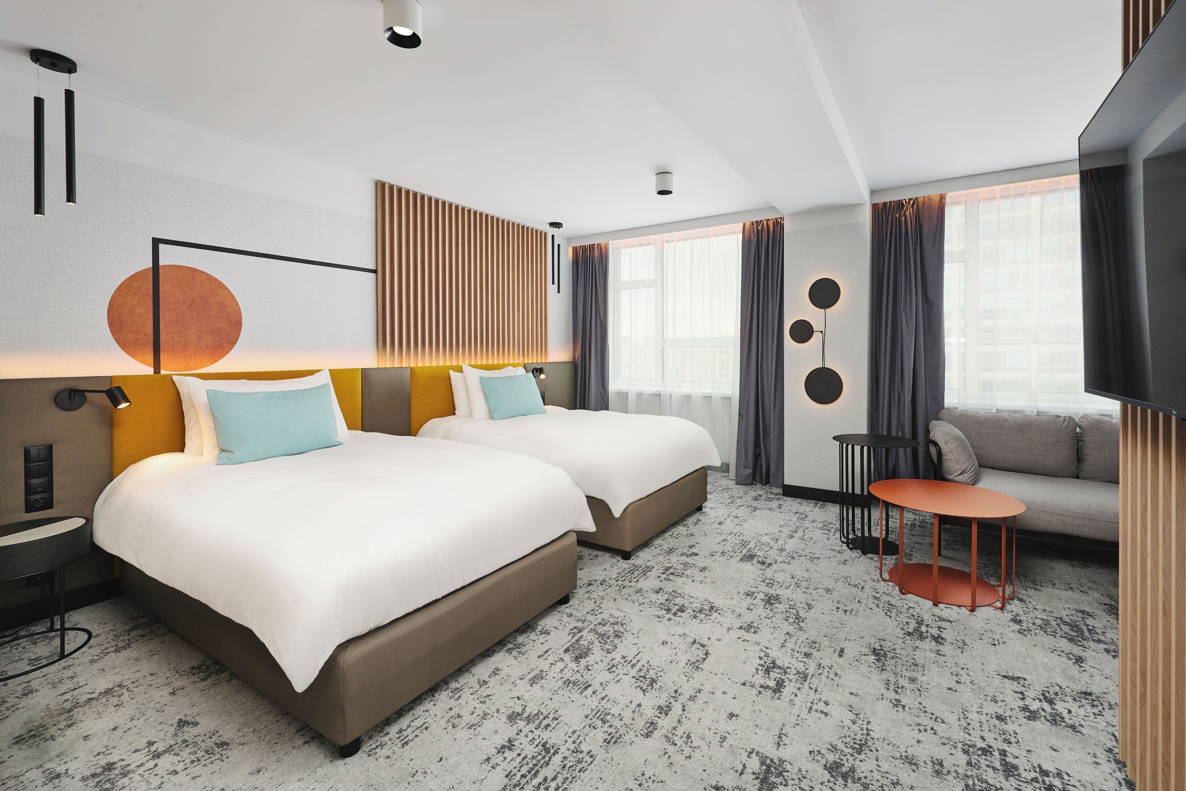 A hotel room with two beds, a sofa, a small table, and a TV.