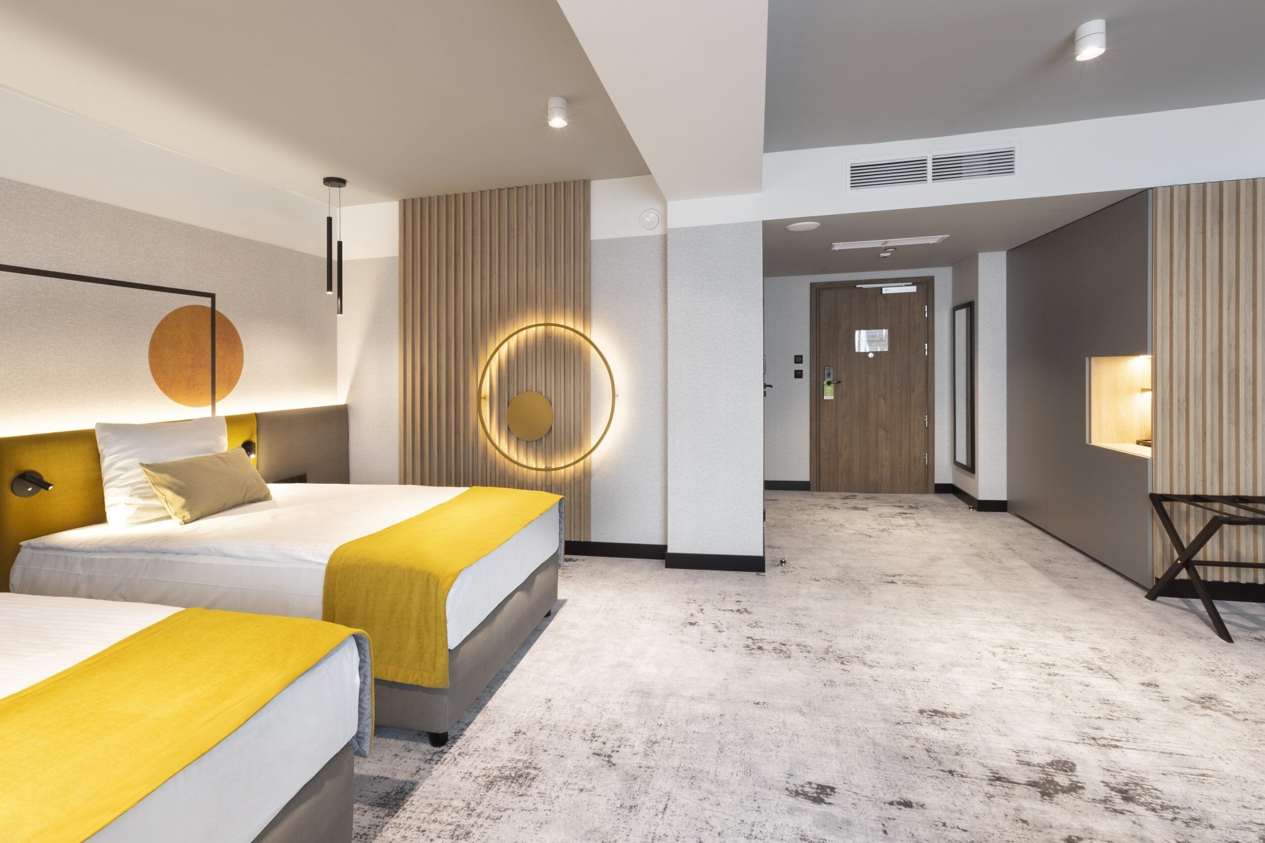 Una habitación de hotel moderna con dos camas, una pared de acento de madera y una lámpara circular.