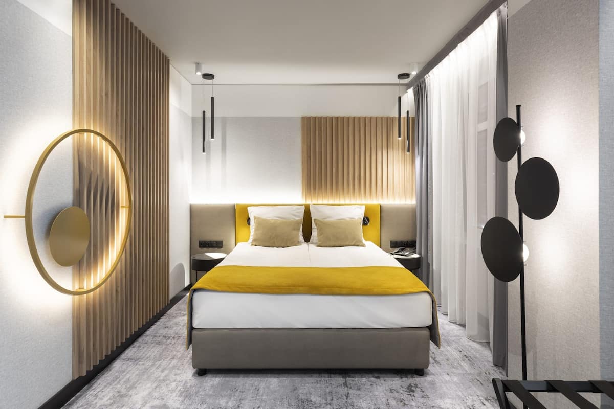 Una habitación de hotel moderna con una cama grande, una lámpara de pared circular y una lámpara de pie.