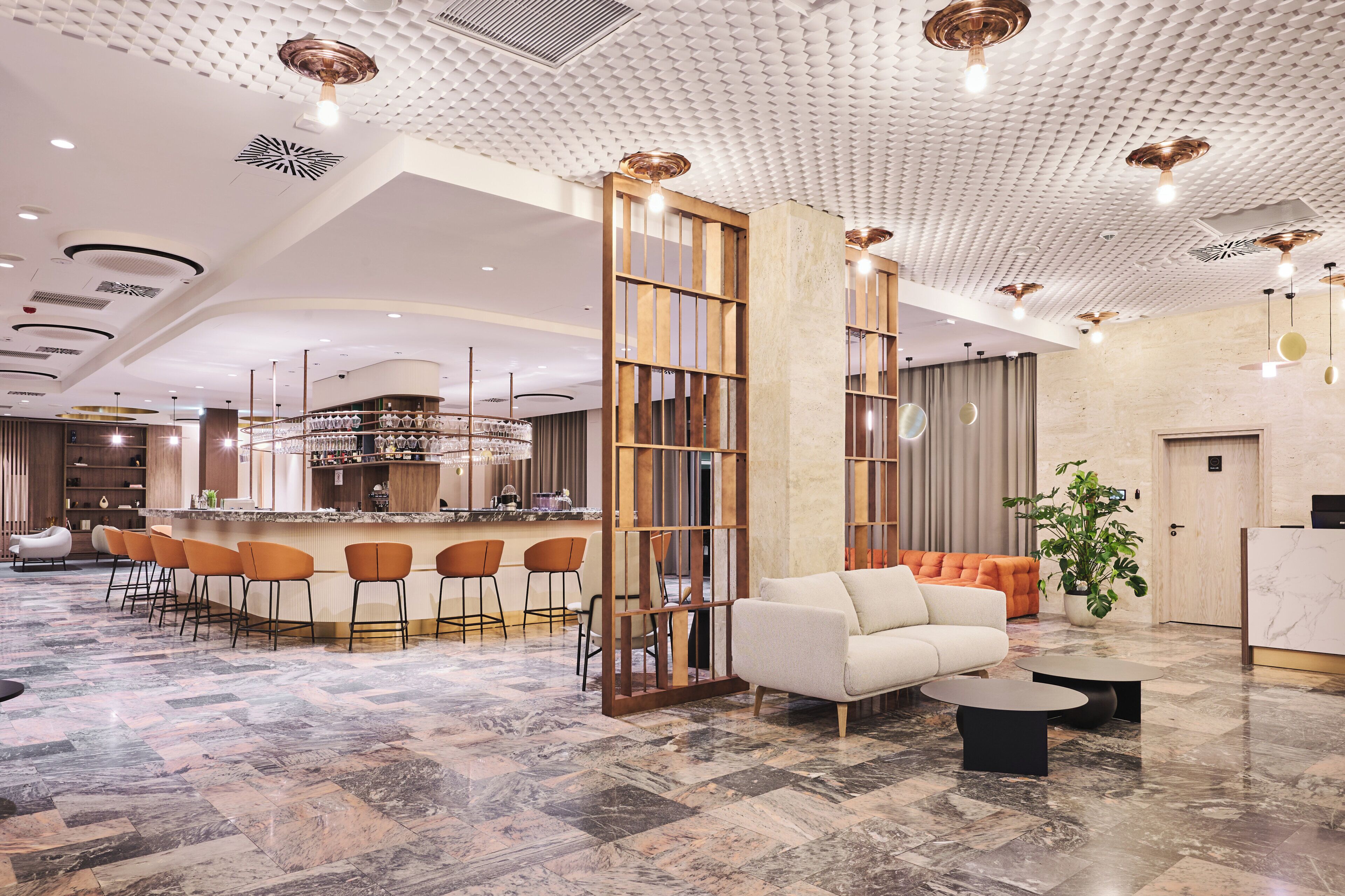 A modern hotel lobby with a bar area, seating, and a reception desk.