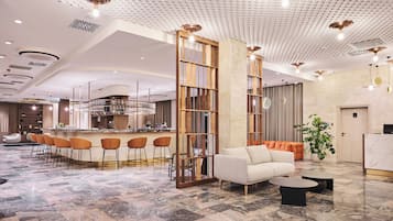 A modern hotel lobby with a bar area, seating, and a reception desk.
