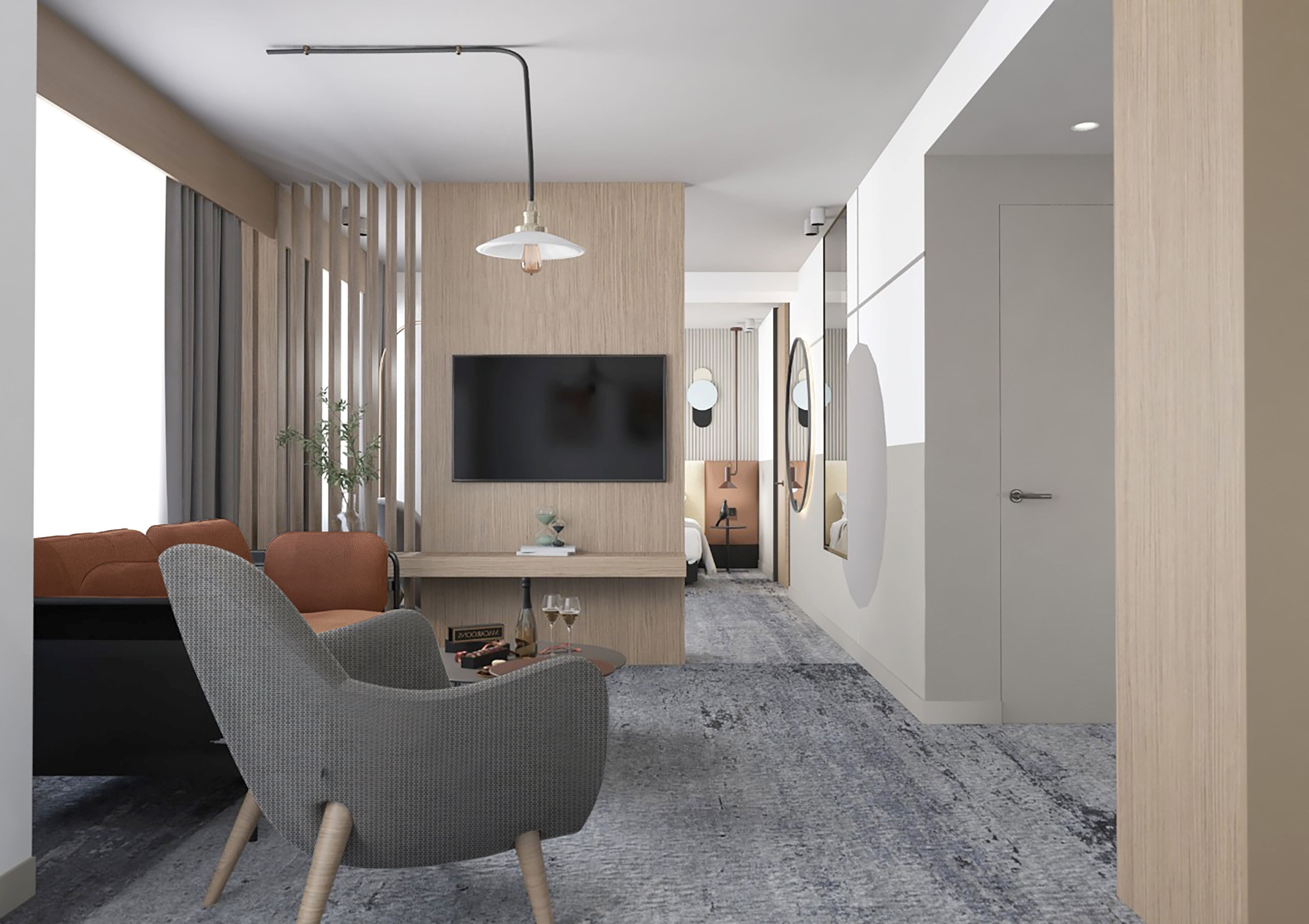 A modern living room with a grey armchair, a wooden TV stand, and a flat-screen TV mounted on the wall.