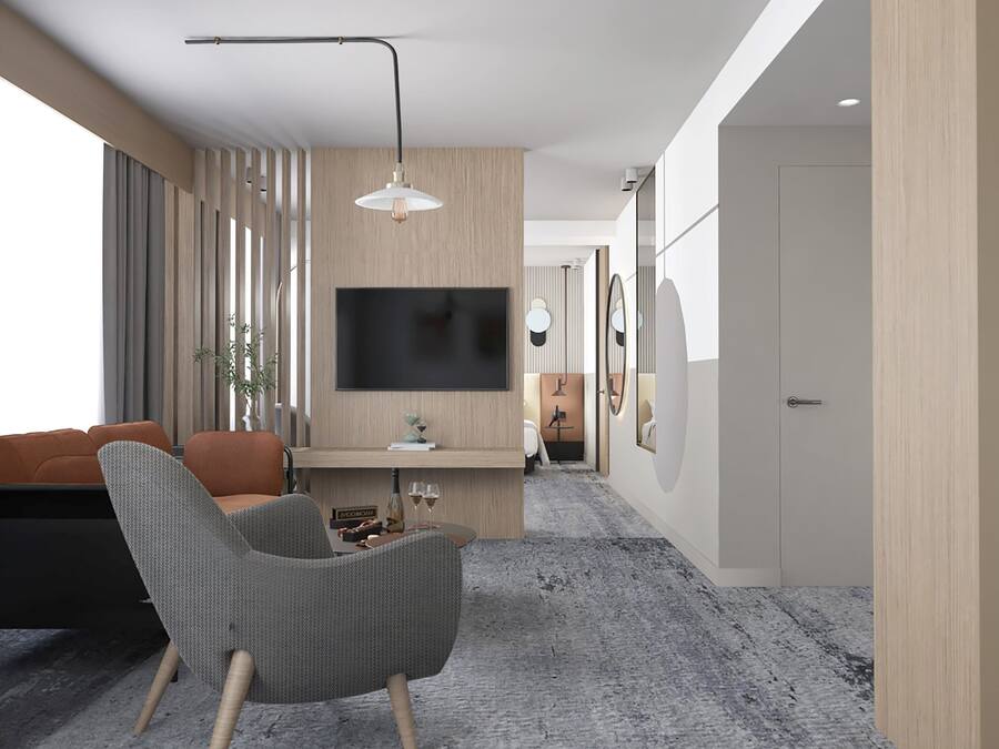 A modern living room with a grey armchair, a wooden TV stand, and a flat-screen TV mounted on the wall.