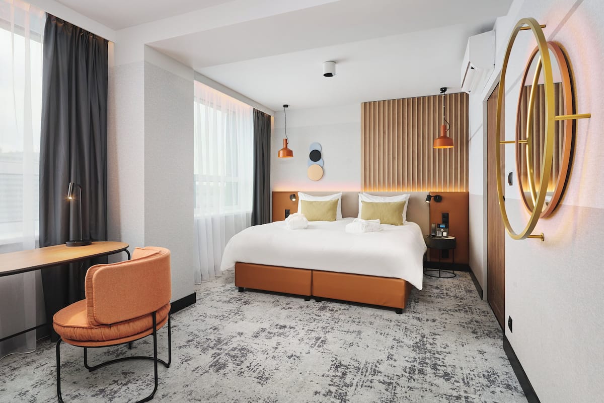 Una habitación de hotel moderna con una cama grande, un escritorio y una silla.