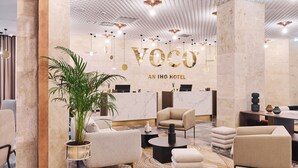 A modern hotel lobby with a reception desk, seating area, and decorative plants. - voco Katowice by IHG (Katowice)
