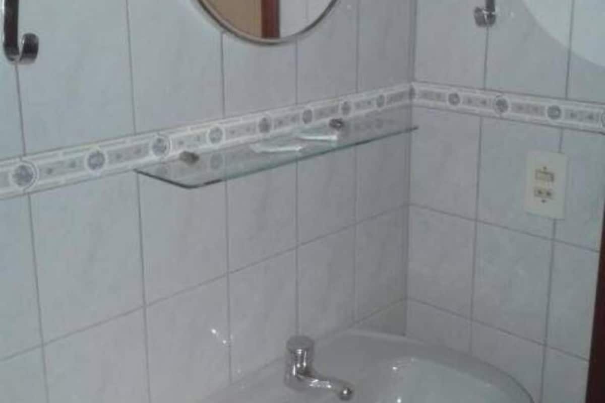 A bathroom with a round mirror, a sink, and a shelf.