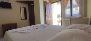 A hotel room with a bed, a television mounted on the wall, a chair, and a window with curtains.