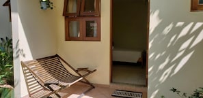 A room with a wooden bench, a window with curtains, and a door leading to another room.