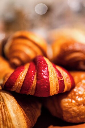 A close-up of croissants with visible layers and a glossy finish. - Lala Hotel (Paris)