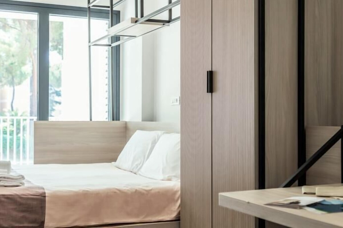 Una habitación de hotel moderna con una cama, una mesita de noche y vistas al exterior.