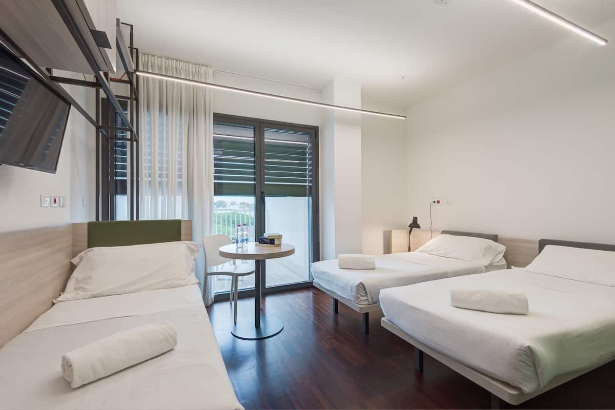 Una habitación de hotel moderna con dos camas individuales, una mesita y una silla.