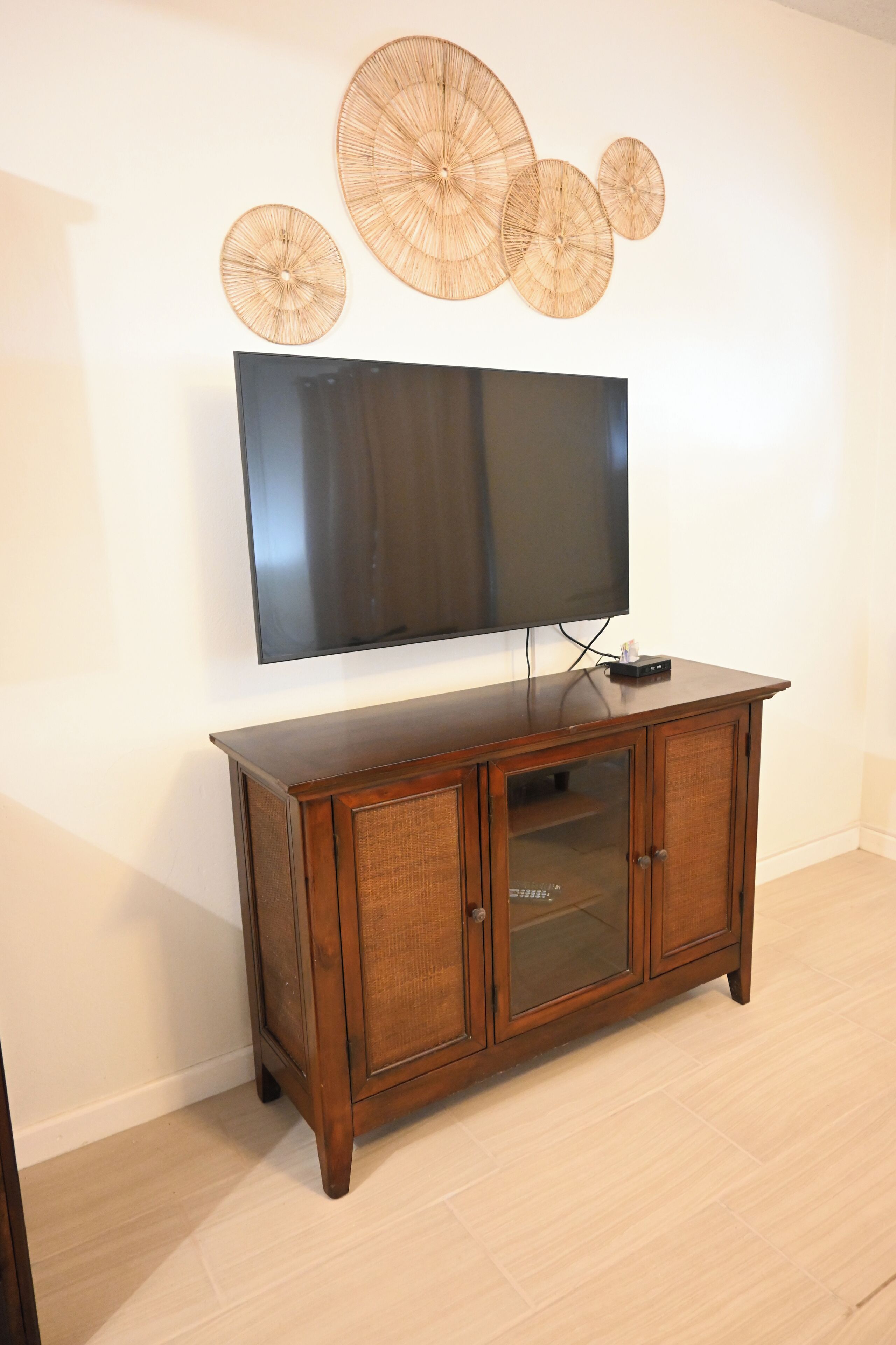 A wooden TV stand with a flat-screen TV mounted above it.