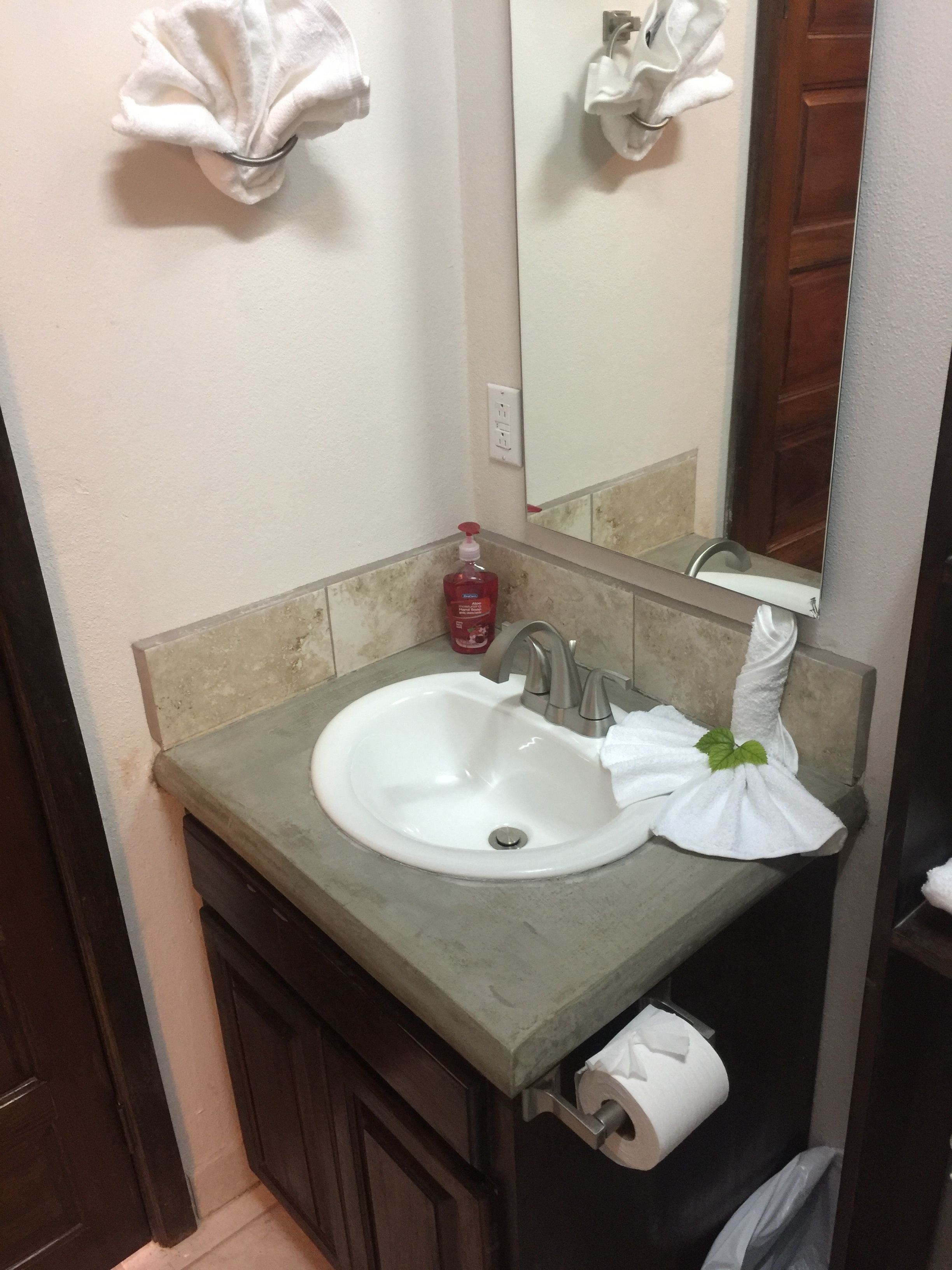 Un baño con lavamanos, espejo y artículos de aseo.