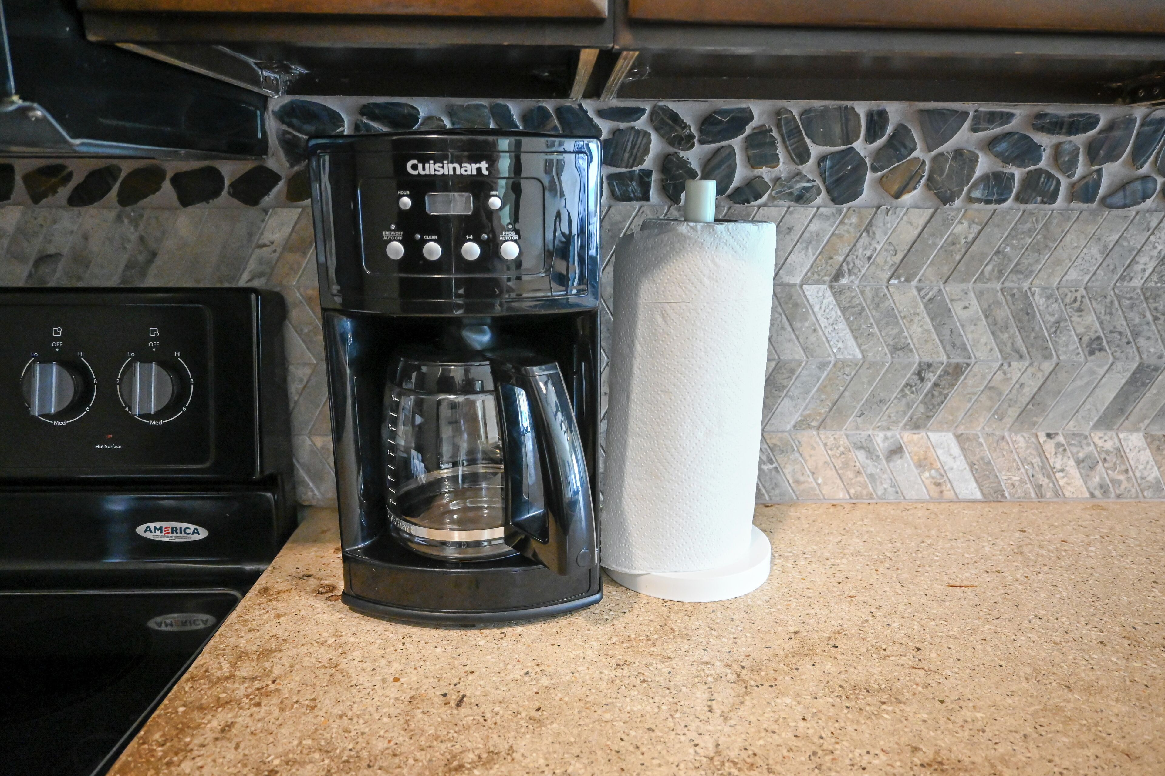 Eine Küche mit Cuisinart-Kaffeemaschine, Papierhandtuchspender und Herd.