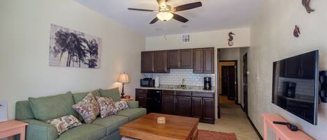 A living room with a green sofa, a wooden coffee table, and a TV.