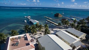 Un hotel frente al mar con varias construcciones, un muelle y aguas azul cristalino.